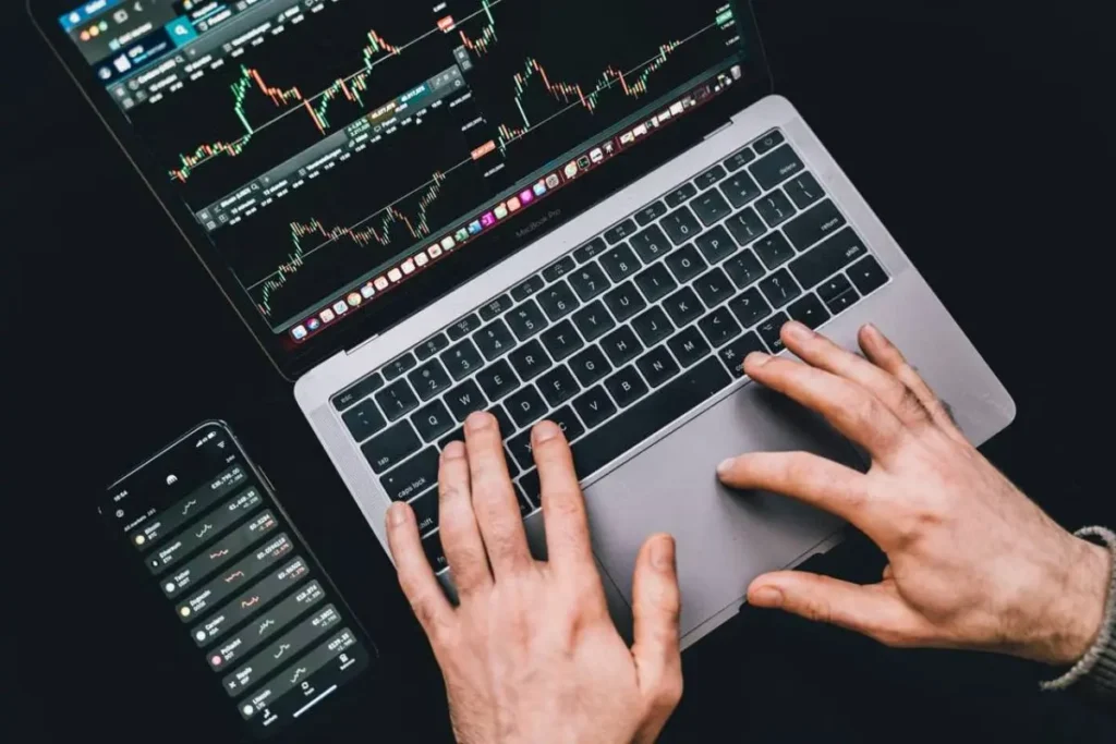 Tangan mengetik di laptop untuk analisis riset pasar saham dan transaksi investasi online