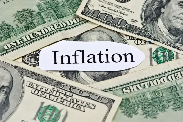 Tumpukan uang kertas dolar dengan tulisan Inflation menggambarkan dampak penurunan nilai mata uang