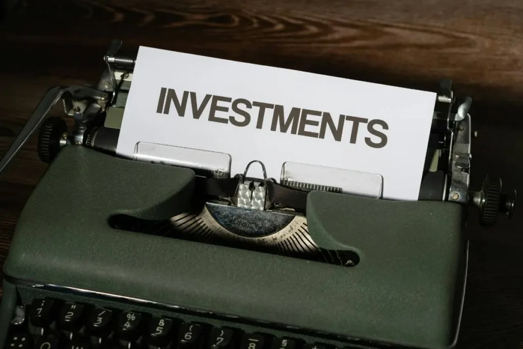 Mesin ketik klasik dengan tulisan INVESTMENTS pada kertas sebagai pengantar topik investasi finansial