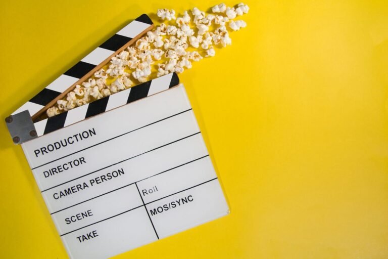 Papan clapperboard dan popcorn di atas latar kuning sebagai ilustrasi berbagai macam genre film.